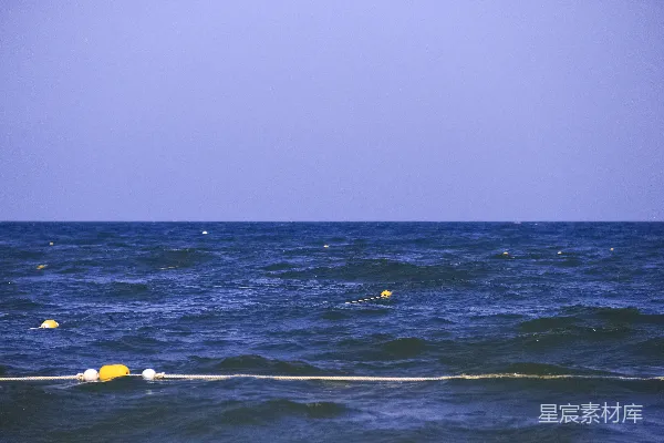高清摄影 黄色的浮标漂浮在波涛汹涌的蓝色海洋上。