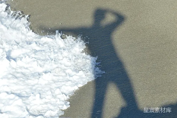 高清摄影 沙滩上一个人影的剪影，海浪拍打着岸边。