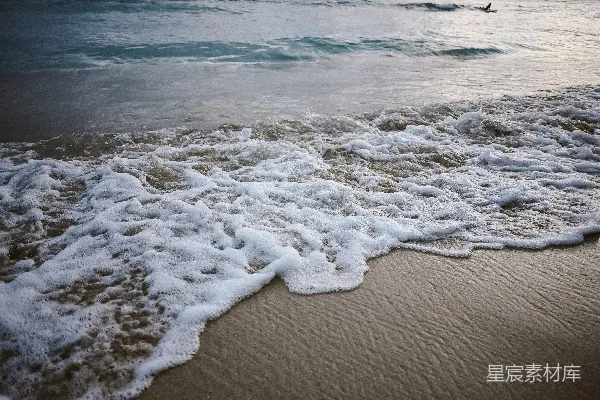 高清摄影 海浪拍打着沙滩，白色的泡沫轻轻拂过。