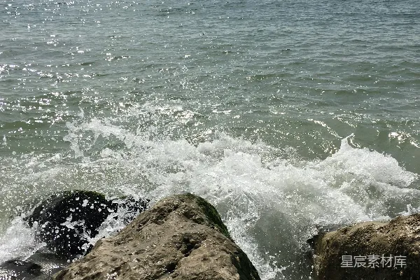 高清摄影 一块大石头坐落在海滩上，旁边是大海。