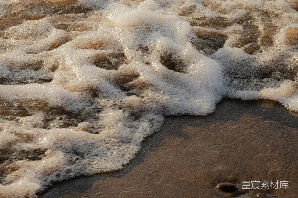 高清摄影 海滩上波浪拍岸，沙滩上有脚印。