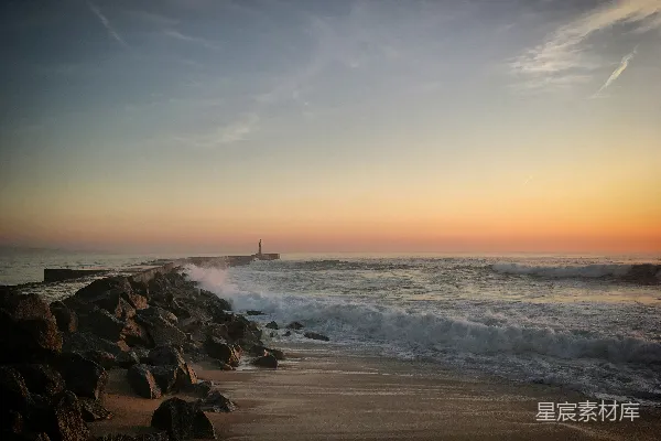 高清摄影 夕阳正缓缓落向海面，远处有一座灯塔。