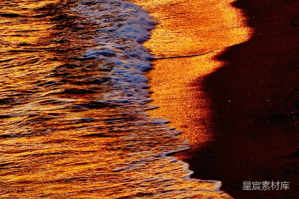 高清摄影 金色的夕阳照耀在海浪和潮湿的沙滩上。