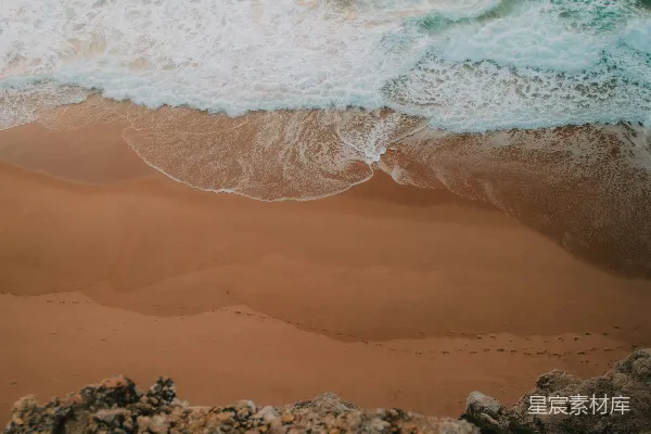 高清摄影 一个沙质海滩，海浪拍打着岸边。