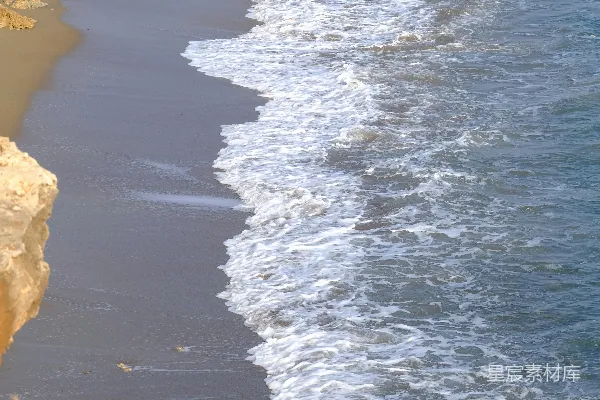 高清摄影 波浪轻轻地拍打着沙滩上的岩石露头。