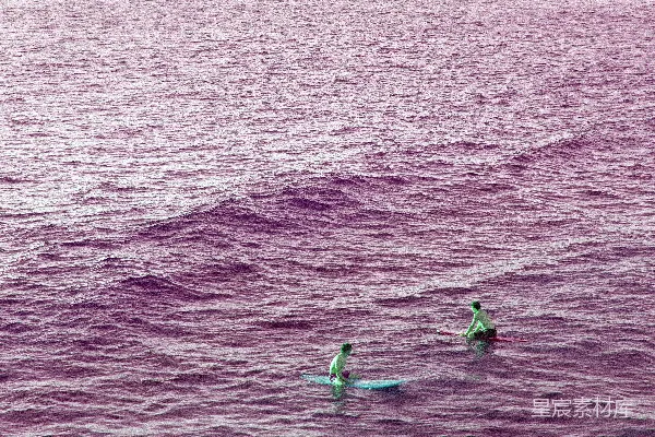 高清摄影 两个在波浪汹涌的海洋上划冲浪板的人。