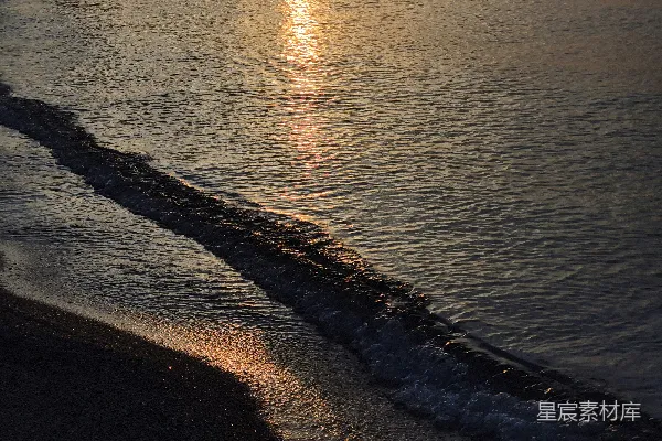 高清摄影 夕阳下，温柔的波浪轻拍着黑暗的海岸。