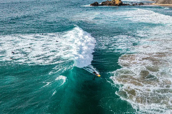 高清摄影 一个冲浪者在岩石海岸线附近驾驭着巨大的海浪。