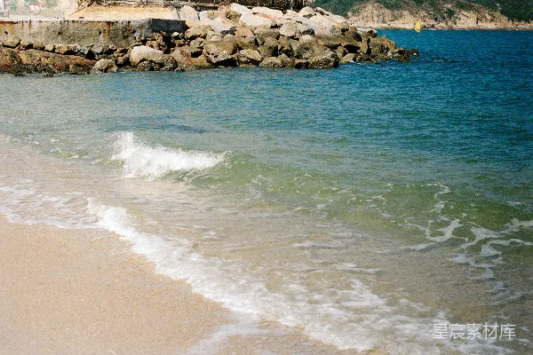 高清摄影 温柔的海浪拍打着岩石旁的沙滩。