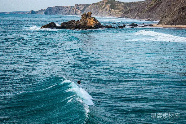 高清摄影 一个冲浪者在崎岖的海岸线附近冲浪。