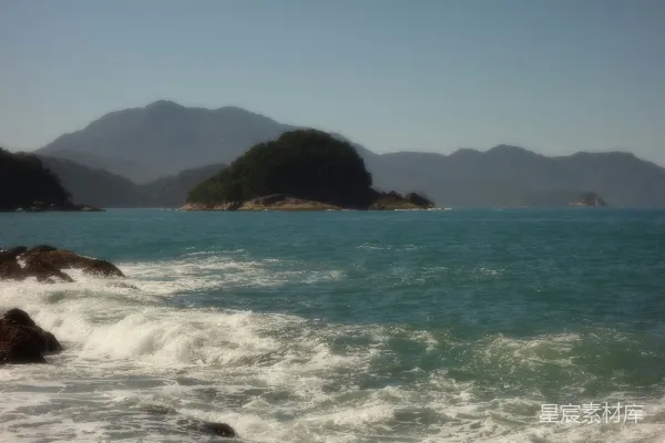 高清摄影 海浪拍打着岩石海岸，远处是岛屿和山脉。