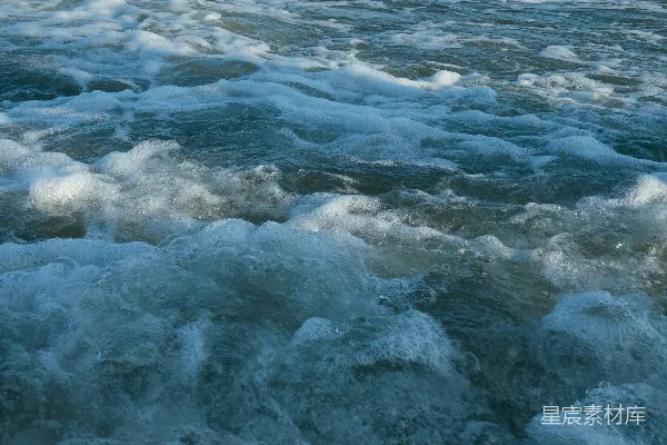 高清摄影 海浪拍打着沙质海滩，冲浪者在其中冲浪。