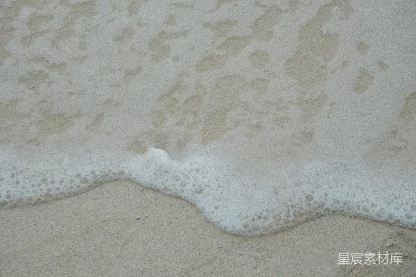 高清摄影 温柔的海浪泡沫轻拂过沙质海滩。