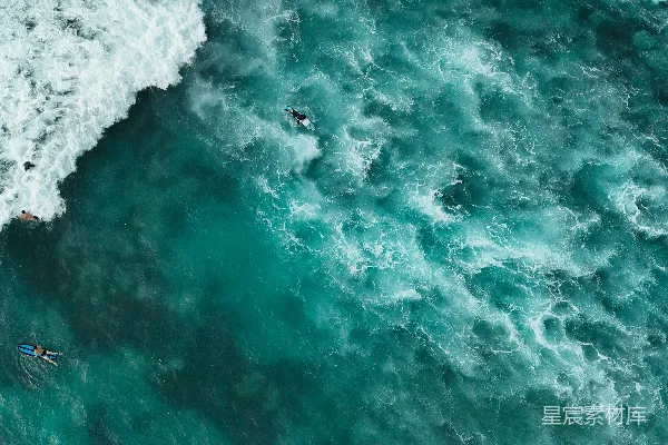 高清摄影 冲浪者在碧绿色的海水中漂浮，海浪正在破碎。