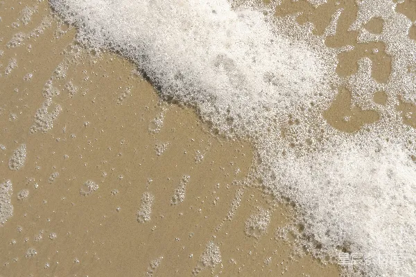 高清摄影 白色的海浪拍打着棕色的沙滩。