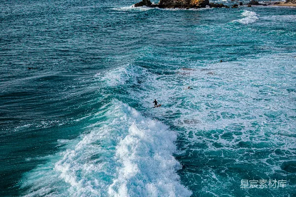高清摄影 冲浪者沿着岩石海岸线驾驭着巨大的海浪。
