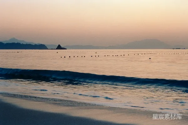 高清摄影 日出时，平静的海浪轻拍着沙滩。