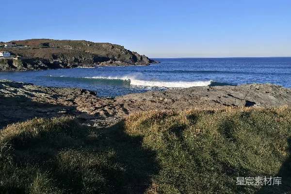 高清摄影 波浪拍打在岩石海岸线上，天空晴朗。