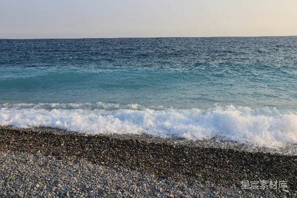 高清摄影 海浪轻柔地拍打着晴空下的一片鹅卵石海滩。