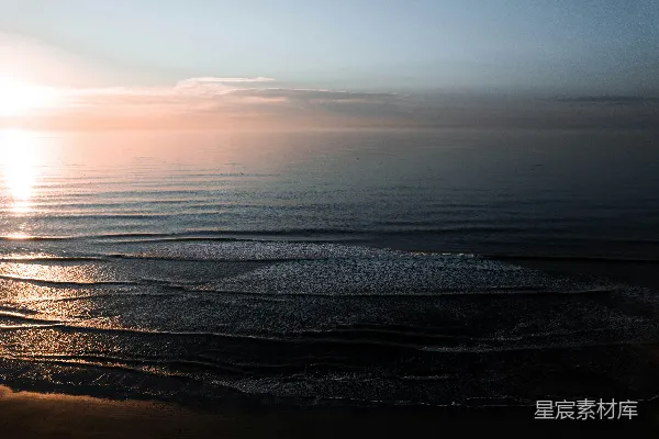 高清摄影 夕阳正缓缓落向海面，海滩上一片宁静。