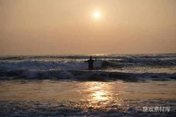 高清摄影 站在夕阳下的海里的人