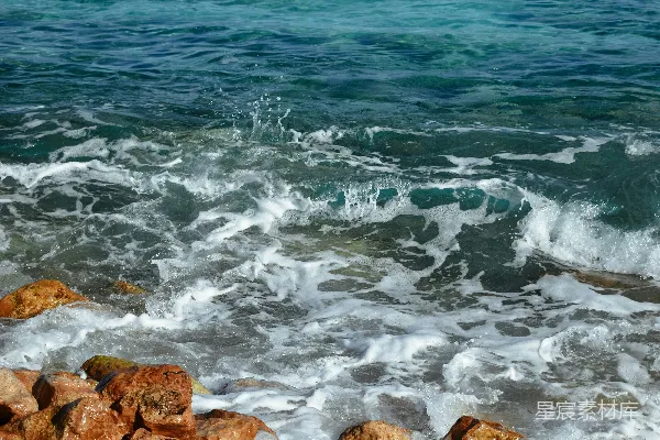 高清摄影 一个男人站在岩石海滩的顶部，海浪拍打着岸边。