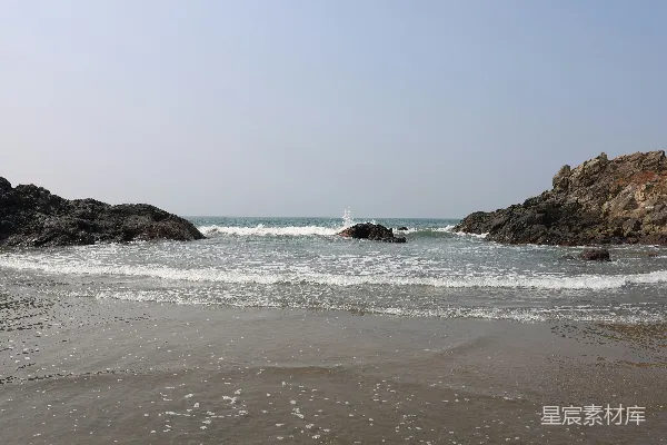 高清摄影 海浪拍打着岩石海滩，天空晴朗无云。