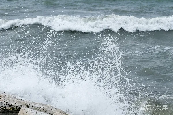 高清摄影 海浪拍打着岩石，远处有一艘船。