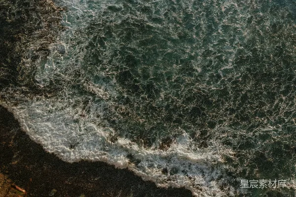 高清摄影 海浪拍打着岩石海岸，岸边绿植丛生。