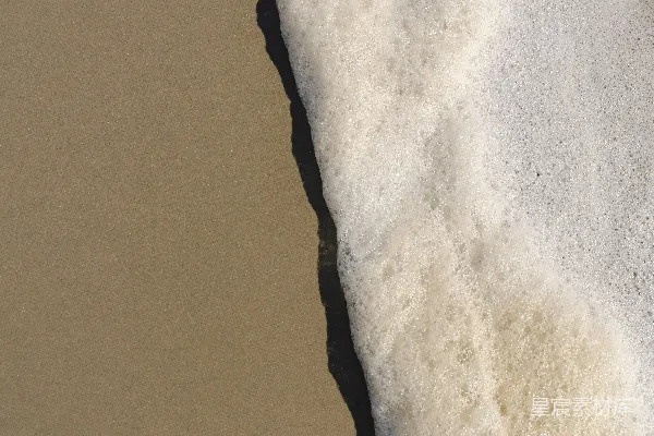 高清摄影 海浪拍打着沙滩，溅起白色的泡沫。