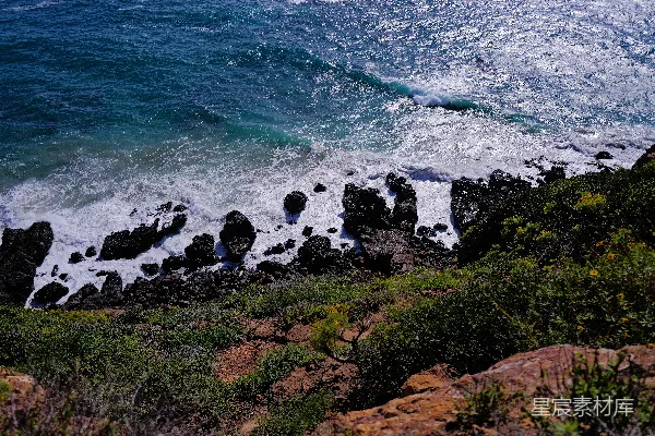 高清摄影 海浪拍打着布满绿色植被的岩石海岸线。
