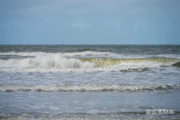 高清摄影 阴沉天空下波涛汹涌的海水，海面上泛起白色的泡沫。