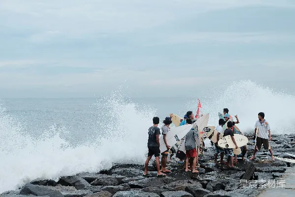 高清摄影 冲浪者在岩石海岸上拿着冲浪板观看海浪