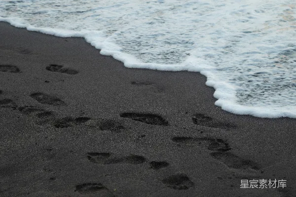 高清摄影 海水冲刷过在黑色火山沙上的脚印。