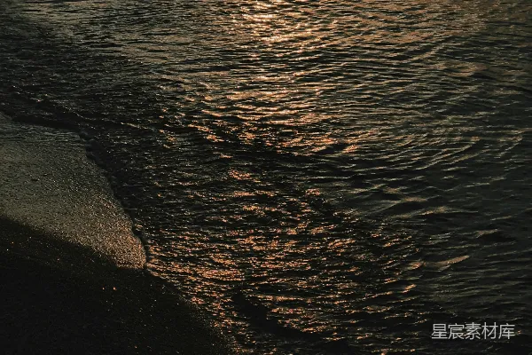高清摄影 金色的夕阳映照在深色、波光粼粼的海面上。