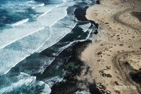 高清摄影 海浪拍打着沙滩，蜿蜒的道路延伸其间。