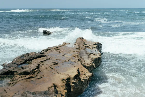 高清摄影 海浪拍打着岩石海岸，在晴朗的天空下。