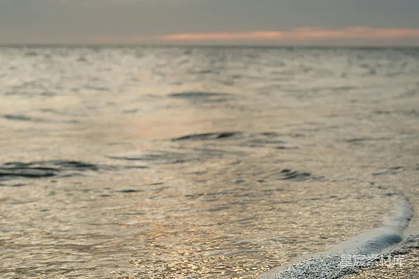 高清摄影 夕阳西下，温柔的海浪轻拍沙滩。