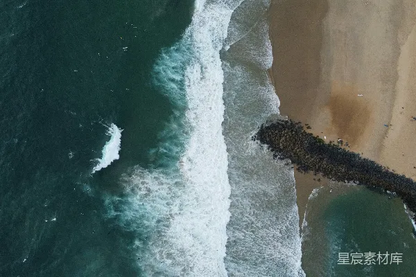 高清摄影 海浪拍打着沙滩，岩石屏障在前景。