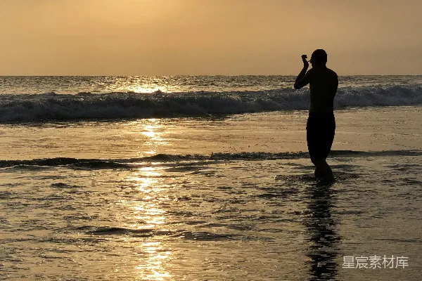 高清摄影 女人站在海滩上的剪影，夕阳西下。
