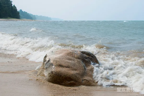 高清摄影 海浪拍打着沙滩上的一块大岩石。