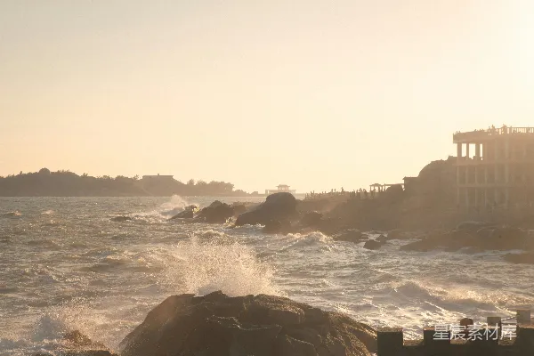 高清摄影 海浪拍打着岩石海岸线，建筑物矗立其中。