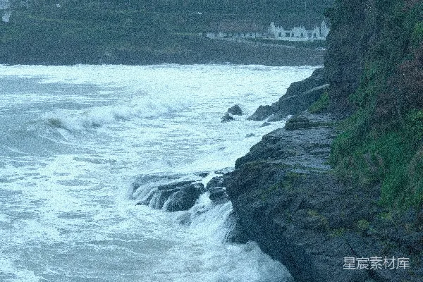 高清摄影 海浪拍打着岩石海岸，背景中有沿海村庄。