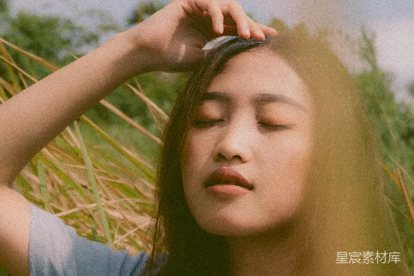 高清摄影 一个女人站在高高的草丛中，闭着眼睛。