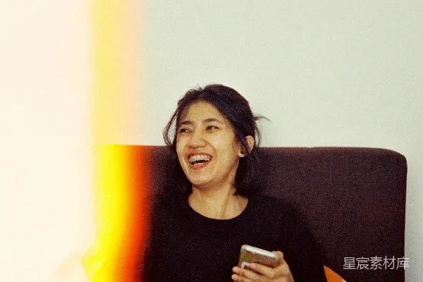 高清摄影 一个女人边笑边拿着手机。