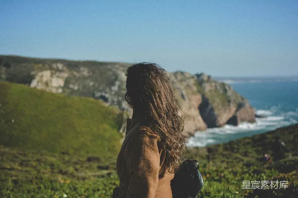高清摄影 女人在白天对着波涛汹涌的海洋看悬崖。