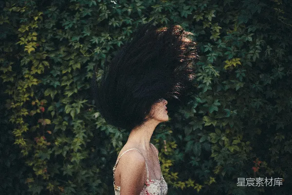 高清摄影 女人在绿色植物墙前挥动着头发