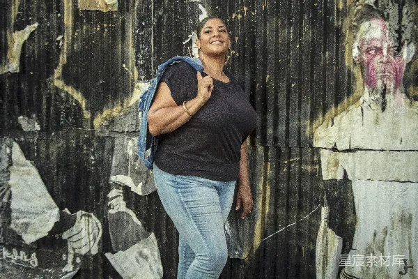 高清摄影 一个女人站在一堵涂鸦覆盖的墙前。