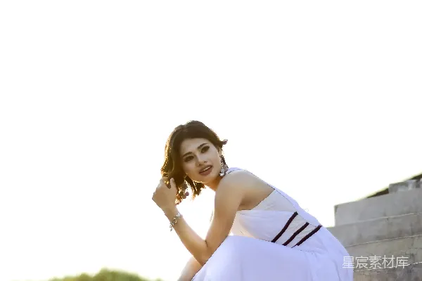 高清摄影 穿着黄色连衣裙的女子坐在混凝土墙上，白天的场景。