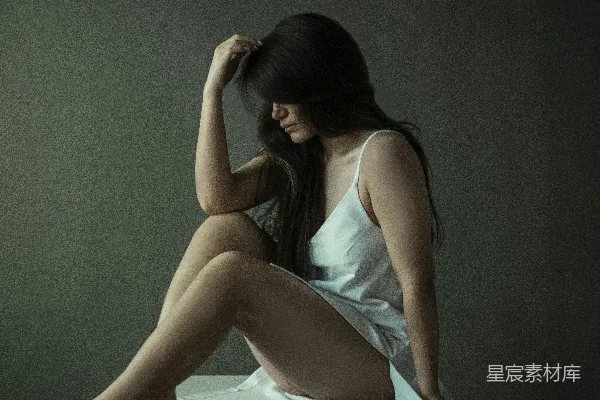 高清摄影 穿着蓝色背心和白色裙子的女人坐在白色纺织品上。